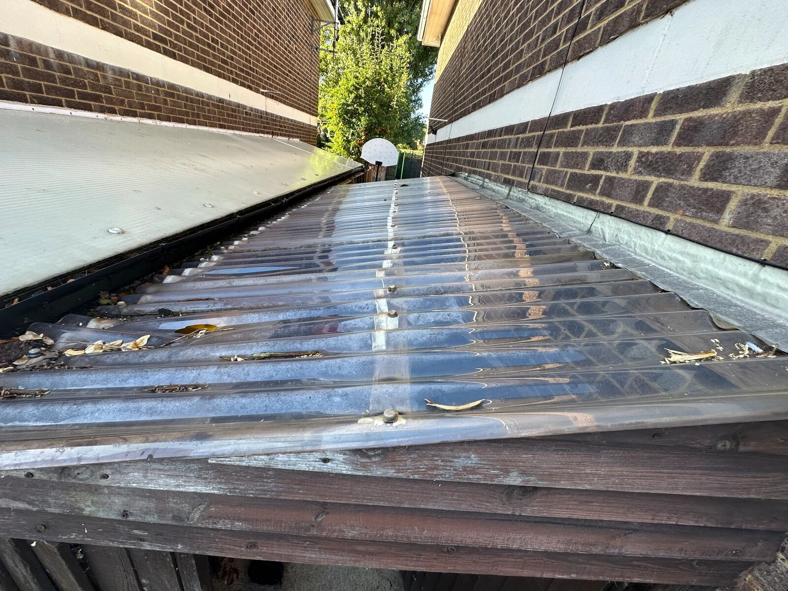 Before: weathered, ageing corrugated plastic lean-to roof viewed from above with old sheets and fixings