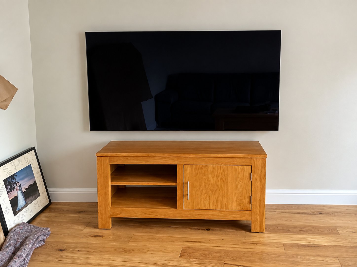 Large flat-screen TV wall mounted on a plasterboard wall above an oak TV cabinet in a Yateley living room